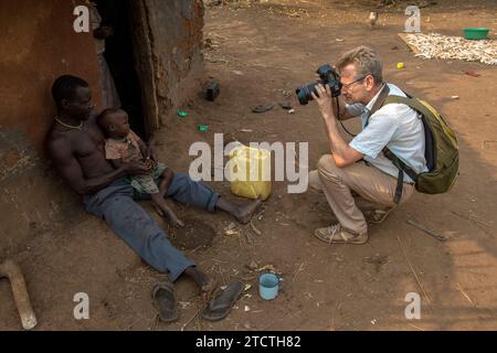 Fotograf, der einen Vater und seinen Jungen in einem abgelegenen Dorf in der westlichen Region, Uganda, erschießt Stockfoto