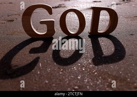 Hölzerne Buchstaben, die das Wort GOTT auf einem Hintergrund aus Strandsand bilden. Christliches Symbol. Stockfoto