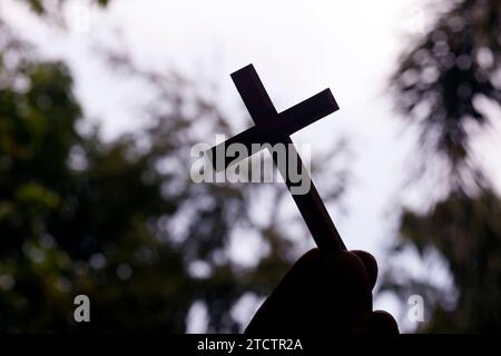 Ein Mann, der ein christliches Kreuz am Himmel hält. Religiöses Symbol des Christentums. Stockfoto