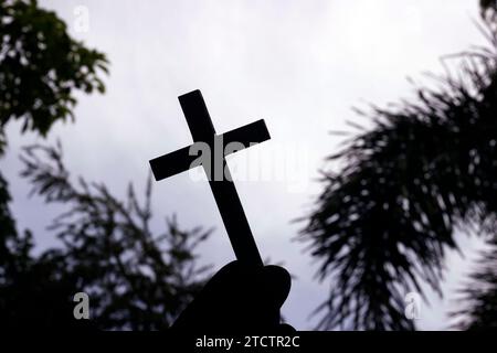 Ein Mann, der ein christliches Kreuz am Himmel hält. Religiöses Symbol des Christentums. Stockfoto