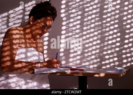 Eine Frau, die einen Brief in ihrem Zimmer mit dem Morgenlicht schreibt. Stockfoto