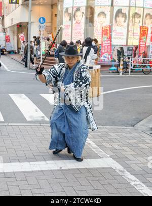 SAMURAI, DIE MÜLL IN DEN SHIBUYA-STRASSEN TOKIO AUFSAMMELN Stockfoto