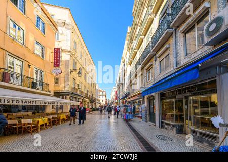 Die beliebte Straße Rua Augusta, in der viele Shopper und Restaurants und Cafés auf dem Bürgersteig in Lissabon, Portugal, genießen. Stockfoto