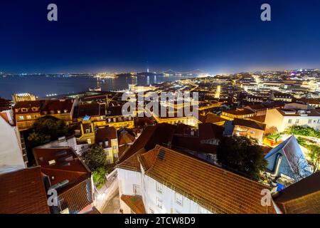 Ein farbenfroher Nachthimmel über der beleuchteten Stadtlandschaft, dem Fluss Tejo und der Brücke Ponte 25 de Abril aus dem Alfama-Viertel in Lissabon, Portugal. Stockfoto