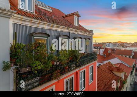 Blick von einer Gasse mit bunten Wohnhäusern und Terrassen im Alfama-Viertel mit Blick auf die Stadt Lissabon Portugal bei Sonnenuntergang. Stockfoto