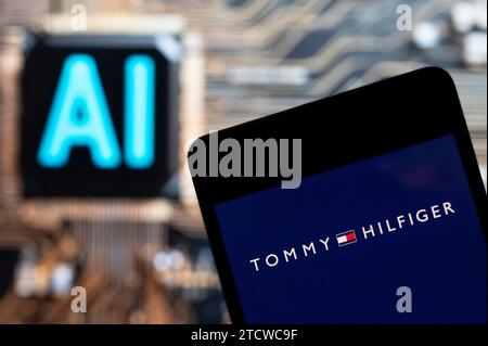 Hongkong, China. November 2023. In dieser Fotoabbildung wird das Logo der amerikanischen Modemarke Tommy Hilfiger auf einem Smartphone mit einem Chip für künstliche Intelligenz (KI) und einem Symbol im Hintergrund angezeigt. (Foto von Budrul Chukrut/SOPA Images/SIPA USA) *** ausschließlich für redaktionelle Nachrichten *** Credit: SIPA USA/Alamy Live News Stockfoto