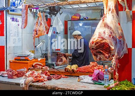 Metzger schneidet Fleisch in der Metzgerei / Metzgerei in der alten Medina der Stadt Fes / Fès, Fès-Meknes, Marokko Stockfoto