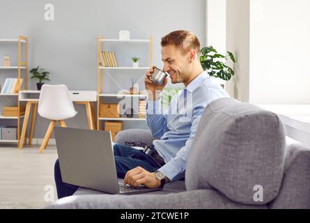 Selbstbewusster attraktiver Mann, der zu Hause auf dem Sofa sitzt und arbeitet oder Online-Videoanrufe hat. Stockfoto