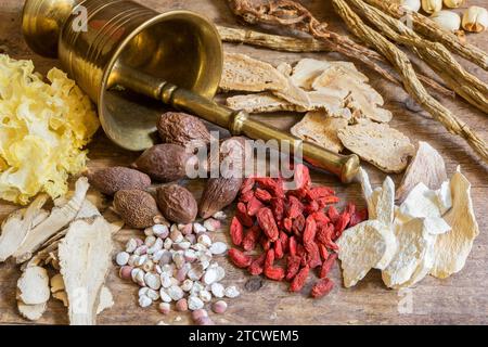 Antike chinesische Medizin mit Bronzemörtel und verschiedenen pflanzlichen Inhaltsstoffen Stockfoto