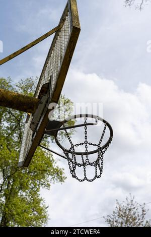 Ein eiserner Basketballkorb im Freien vor blauem Himmel. Basketballkorb mit Eisennetz Stockfoto