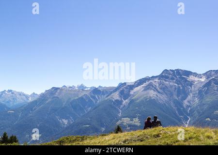 Riederalp, Schweiz - 05. August 2020: Wanderparadies in der Alsp mit Trekkingern, die sich auf der Wiese ausruhen - Kopierraum Stockfoto