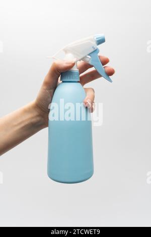 Kunststoff-Sprühflasche in der Hand isoliert auf weißem Hintergrund. Sprühen Sie die Flasche in der Hand auf weißem Hintergrund. Stockfoto