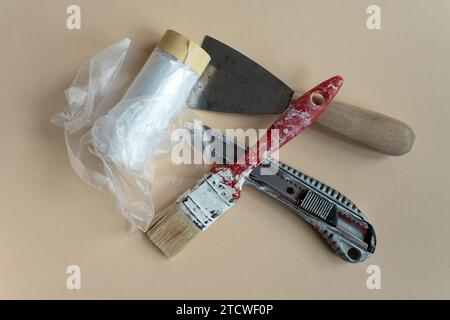 Eine Reihe von Malerwerkzeugen. Ein Pinsel, ein Spachtel und ein Messer für den Baumeister. Abdeckband. Handwerk. Eine Reihe von Malerwerkzeugen Stockfoto