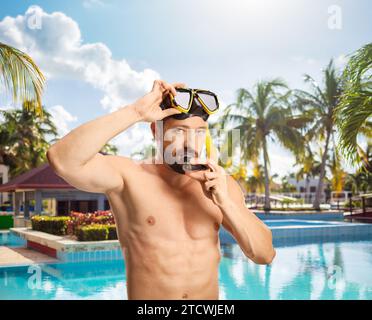 Junger Mann, der eine Tauchermaske an einem Schwimmbad anzieht Stockfoto