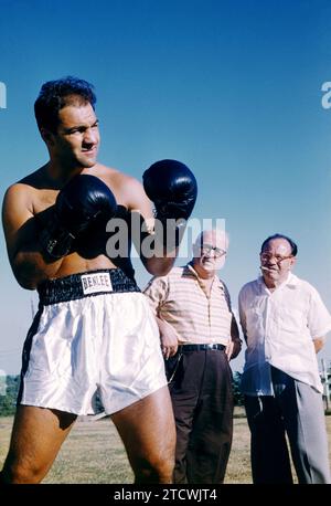 FERNDALE, NY – 8. AUGUST: Der US-amerikanische Boxer Rocky Marciano (1923–1969) posiert für ein Porträt, während sein Manager Al Weill und Trainer Charlie Goldman am 8. August 1955 in Ferndale, New York, im Grossinger's Resort anschauen. (Foto von Hy Peskin) *** örtlicher Bildtitel *** Rocky Marciano;Al Weill;Charlie Goldman Stockfoto