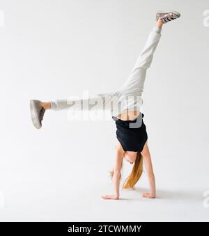 Attraktives flexibles Teenager-Mädchen, das Handstand auf hellem Hintergrund macht Stockfoto