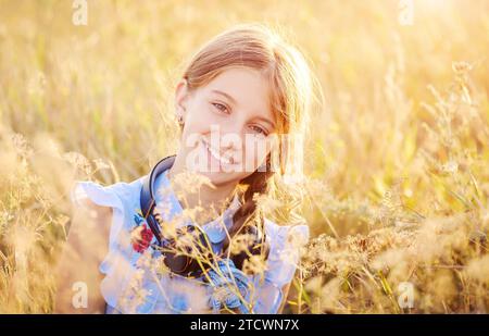 Lächelndes Teenager-Mädchen mit Kopfhörern auf Sonnenfeld Hintergrund Stockfoto