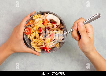 Essen Sie einen Nudelsalat mit Pilzscheiben, Tomaten, roten Pfefferstückchen und Thunfisch, gesunde Lebensmittel mit Gemüse, frische Bio-Ernährung Stockfoto