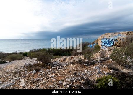 Blick über den Strand bis zum Meer in der Nähe von Martigues in Frankreich. Auf der rechten Seite sehen Sie einen alten Bunker aus dem Zweiten Weltkrieg, der mit Farbe bedeckt ist. Stockfoto