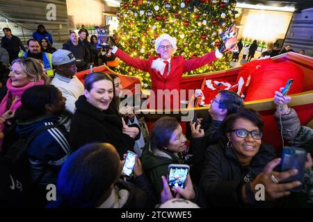 NUR REDAKTIONELLE VERWENDUNG Gary Lineker überrascht die Öffentlichkeit, indem er einen Schlitten voller Walkers-Crisps durch die Battersea Power Station im Süden Londons fährt, während er als „Father Crisp-MAS“ gekleidet ist, um sein 30. Jahr bei der Arbeit mit der Marke zu feiern. Bilddatum: Donnerstag, 14. Dezember 2023. Stockfoto