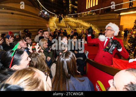 NUR REDAKTIONELLE VERWENDUNG Gary Lineker überrascht die Öffentlichkeit, indem er einen Schlitten voller Walkers-Crisps durch die Battersea Power Station im Süden Londons fährt, während er als „Father Crisp-MAS“ gekleidet ist, um sein 30. Jahr bei der Arbeit mit der Marke zu feiern. Bilddatum: Donnerstag, 14. Dezember 2023. Stockfoto