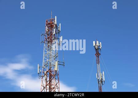 Mobile Telekommunikationstürme am blauen Himmel mit weißen Wolken. Mobilfunkturm mit Antennen und elektronischen Kommunikationsgeräten Stockfoto