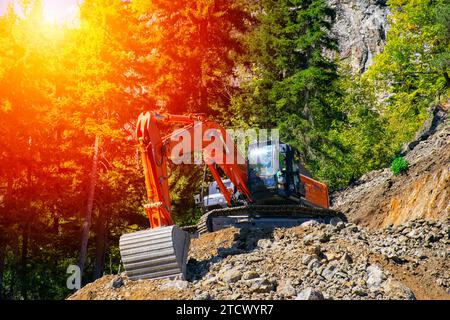 Bagger auf der Baustelle am Hang eines Hügels gegen Sonnenuntergang. Stockfoto