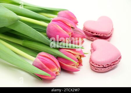 Blumenstrauß frischer rosafarbener Tulpen mit rosa herzförmigen makroons in Nahaufnahme. Stockfoto
