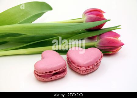 Blumenstrauß frischer rosafarbener Tulpen mit rosa herzförmigen makroons in Nahaufnahme. Stockfoto