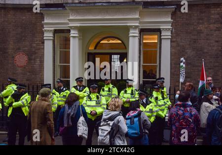 London, Großbritannien. Dezember 2023. Polizisten bewachen den Eingang während der Demonstration. Pro-palästinensische Demonstranten versammelten sich vor einer Spendenaktion für Israel in der Royal Society for Arts, in der der israelische Botschafter Tzipi Hotovely und der israelische Präsident Isaac Herzog teilnahmen. Quelle: SOPA Images Limited/Alamy Live News Stockfoto