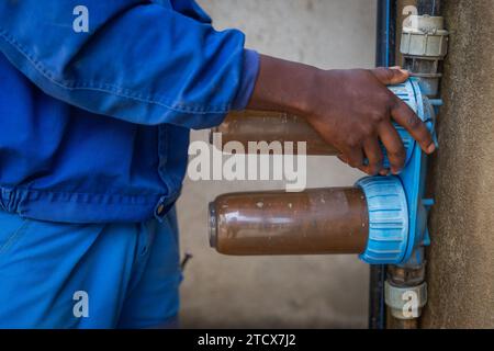 Nahaufnahme der Hände des Klempners, die Schmutzwasserfilter lösen, um sie auszuwechseln. Stockfoto