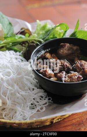 Brötcha nach Hanoi-Art mit gegrilltem Schweinefleisch und Fleischbällchen, Reisnudeln, frischem Salat und Kräutern (Minze, Perillablatt, Koriander) Stockfoto