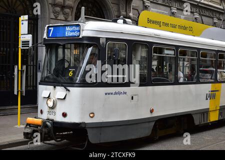 Weiß-gelbe Straßenbahn Nr. 7 in Antwerpen mit Endstation „Mortsel Eilandje“ und Banner-Text oben auf Niederländisch „Move along towards less CO2“ Stockfoto