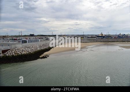 Ein kleiner Sandstrand vor dem Betonpier, geschützt durch Steinblöcke im Calais Auto Fährhafen Stockfoto