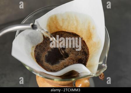 Gießen Sie heißes Wasser in eine chemex-Glaskaffeemaschine mit Papierfilter und Kaffee, Nahaufnahme Stockfoto