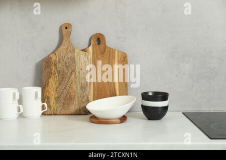 Schneidebretter und Geschirr aus Holz auf weißer Arbeitsplatte in der Küche Stockfoto