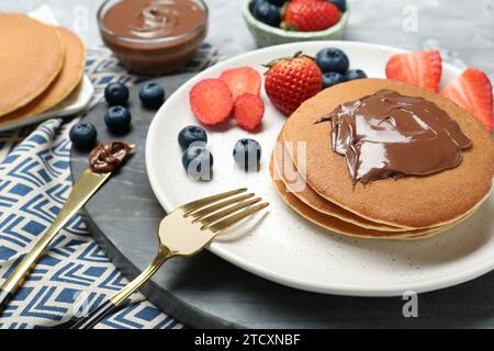 Leckere Pfannkuchen mit Schokoladenpaste und Beeren auf dem Tisch, Nahaufnahme Stockfoto