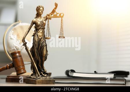 Symbol für eine gerechte Behandlung nach dem Gesetz. Statue von Lady Justice, Hammer und Notizbücher auf dem Tisch drinnen, Platz für Text Stockfoto