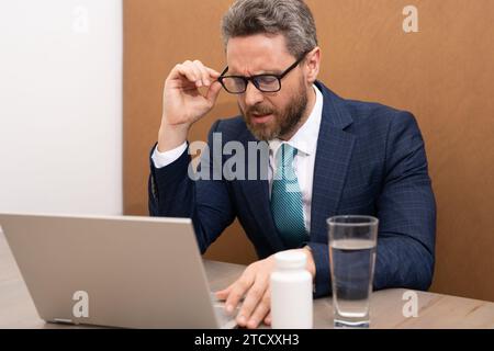 Geschäftsmann fühlt Schmerzen beim Brillenhalten trockene, gereizte Augen ermüdet von Computerarbeit, gestresster Mann leidet an Kopfschmerzen schlechtes Sehvermögen Stockfoto