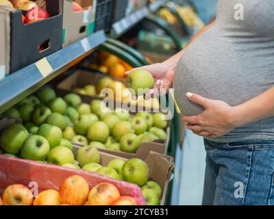 Schwangere Frau wählt Äpfel im Laden. Stockfoto