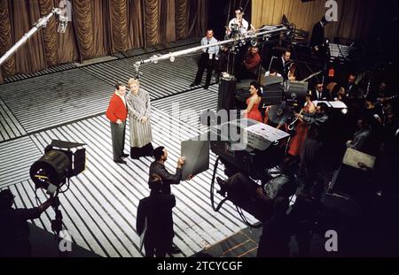 NEW YORK, NEW YORK - 1957: Die amerikanische Sängerin und TV-Persönlichkeit Perry Como (1912-2001), US-amerikanische Schauspielerin, Comedian und Sängerin Judy Holliday (1921-1965) auf der Bühne während "Durchführen der Perry Como Show" ca. 1957 in New York, New York. (Foto von Hy Peskin) *** Local Caption *** Perry Como; Judy Holliday Stockfoto