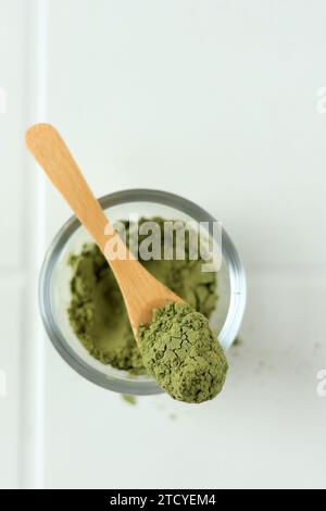 Top View Green Matcha Teepulver auf Holzlöffel auf weißem Tischhintergrund. Stockfoto