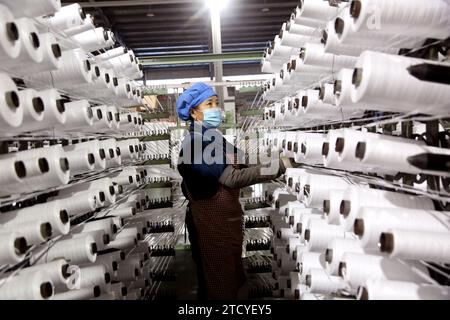 LIANYUNGANG, CHINA - 15. DEZEMBER 2023 - Ein Arbeiter beeilt sich, in einer Werkstatt für die Herstellung von gewebten Taschen in der Stadt Lianyungang, Provinz Jiangsu, CH, eine Bestellung zu erteilen Stockfoto