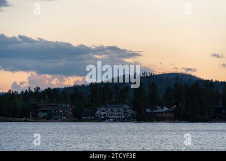 Der Abend geht in den ruhigen Häusern am See in Grand Lake, Colorado, unter einer Bergsilhouette hinunter. Stockfoto