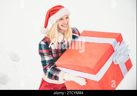Santa Woman hält eine große Geschenkbox mit Kopierraum für Ihre SMS. Weihnachtsmädchen mit einem großen Geschenk. Große Geschenkbox. Das verrückte Weihnachtsmädchen schiebt eine große Stockfoto