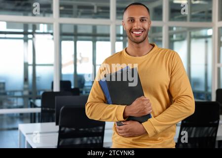 Glücklicher Mann mit Klemmbrettern im Büro, Platz für Text Stockfoto