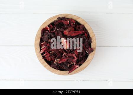 Hibiskus-Tee. Schüssel mit getrockneten roselle-Kelchen auf weißem Holztisch, Draufsicht Stockfoto