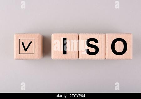 Internationale Organisation für Normung. Holzwürfel mit Häkchen und Abkürzung ISO auf hellgrauem Hintergrund, flache Lagen Stockfoto