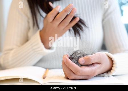 Eine Frau, die an Alopezie leidet, hält ihr Haar in den Händen Stockfoto