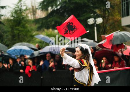Tirana, Albanien - 28. November 2023: Auf der Avenue der Märtyrer der Nation, in der Nähe von Mutter Teresa Palace, spaziert eine Frau in traditioneller Kleidung jubelnd mit ihr Stockfoto